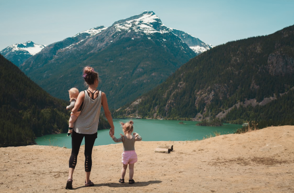 Mother and children walking along lake with mountains behind